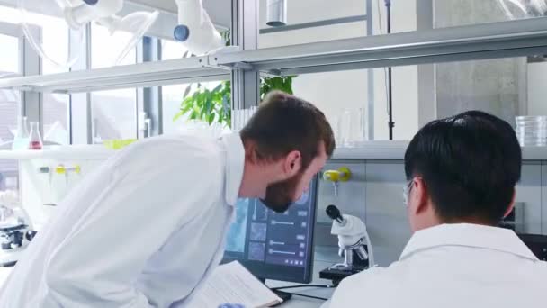 Scientist and his assistant working in lab. Doctor teaching intern to make analyzing research. Laboratory tools: microscope, test tubes, equipment. - Footage, Video