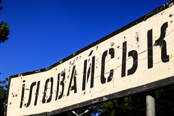 Road sign with the inscription in Ukrainian Illowaysk, Donetsk region, broken by bullets during the war in the , Ukraine. Armed conflict east of Ukraine, destruction in ATO. - Photo, Image