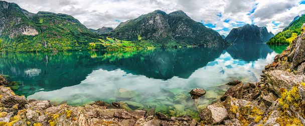 Norwegian landscape with Reflections in the calm water of the Norwegian crystal clear lake with a rocky bottom and green mountains. Oppstryn, Norway. - Photo, Image