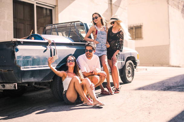 A group of friends are taking a selfie with a blue car - Foto, Imagem