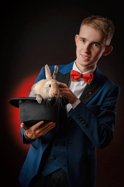 Nuori mies taikuri illuusio, jolla on hattu kanin kanssa. - Valokuva, kuva
