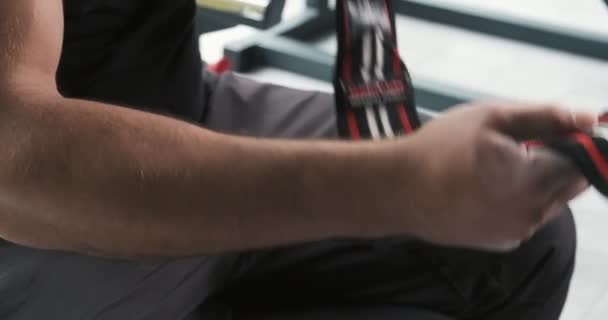 El joven musculario está vendando el brazo con vendas en el gimnasio antes de entrenar. Movimiento lento
 - Metraje, vídeo