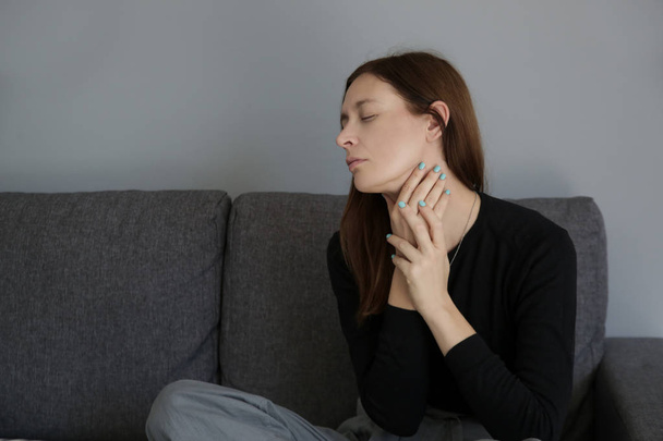 Фотографія молодої жінки, яка страждає від болю в горлі або синдрому проблеми щитовидної залози
 - Фото, зображення