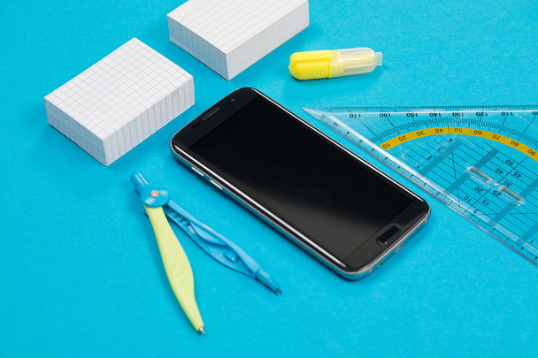 Deux piles de papier à gratter blanc, une paire de boussoles, une règle, un marqueur de texte jaune et un smartphone noir sur fond azur isolé
 - Photo, image