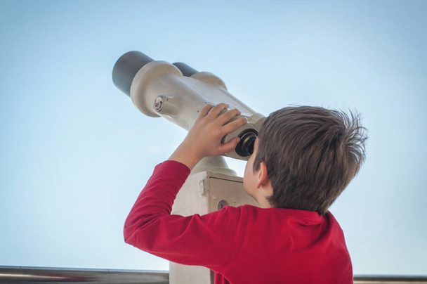 o menino observa o telescópio turístico em
 - Foto, Imagem