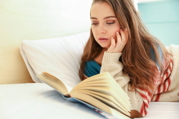 czytając książkę w łóżku nastolatek - Zdjęcie, obraz