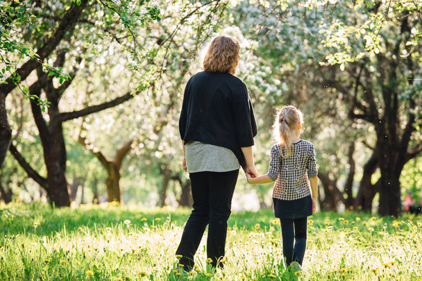 Mother and daughter having fun in the park. Happiness and harmony in family life.  Beauty nature scene with family outdoor lifestyle. Woman and cheerful little girl - 写真・画像