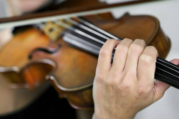 Hand einer Geigerin auf dem Griffbrett einer Geige aus nächster Nähe - Foto, Bild