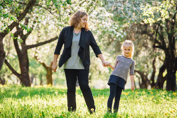 Mother and daughter having fun in the park. Happiness and harmony in family life.  Beauty nature scene with family outdoor lifestyle. Woman and cheerful little girl - 写真・画像