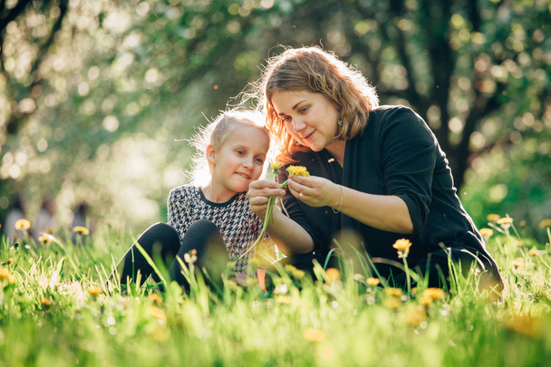 Mother and daughter having fun in the park. Happiness and harmony in family life.  Beauty nature scene with family outdoor lifestyle. Woman and cheerful little girl - Foto, Bild
