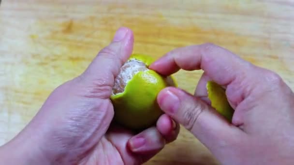 Girl peeling orange and hold it in hand,  close up over wooden cutting board. - 映像、動画