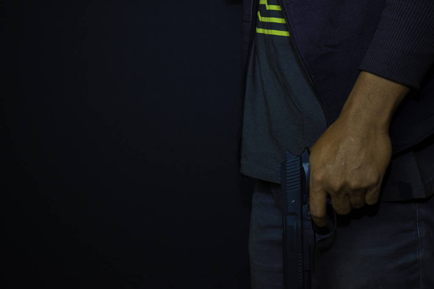 ázsiai ember tartja a fegyvert. Gun a kezében izolált fekete háttér. - Fotó, kép