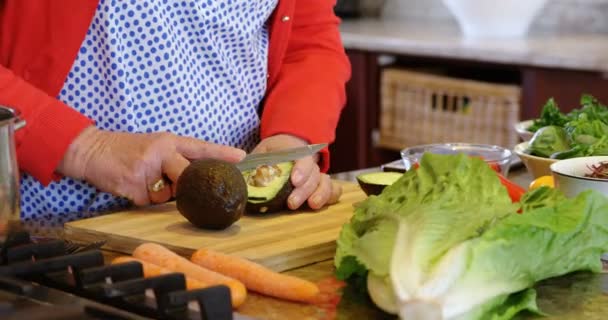 Střední část starší ženy sekání zeleniny v kuchyni doma  - Záběry, video