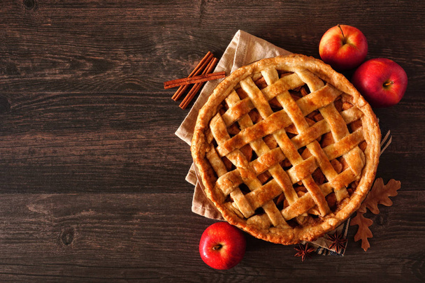 Homemade autumn apple pie, top view with frame of ingredients on a dark wood table with copy space - Foto, Imagen