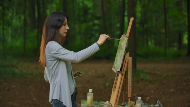 Girl artist painting a picture then turns to the camera and smiles. - 映像、動画