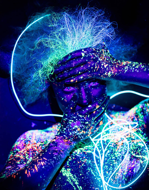 Body art and contact lenses glowing in ultraviolet light. Portrait of a woman painted in fluorescent powder. Stars in the eyes. Neon light ribbon. - Fotoğraf, Görsel
