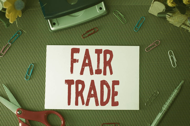 Handwriting text Fair Trade. Concept meaning Small increase by a analysisufacturer what they paid to a producer Scissors and writing equipments plus plain sheet above textured backdrop. - Photo, Image