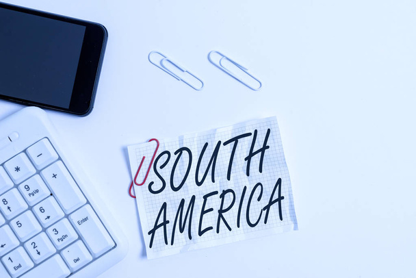 Text sign showing South America. Conceptual photo Continent in Western Hemisphere Latinos known for Carnivals White pc keyboard with empty note paper above white background and mobile phone. - Foto, Imagem