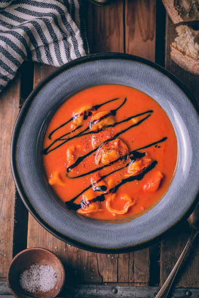 Autumn red tomato cream soup with homemade cheese tortellini and topped with balsamic reduction. Soup bowl in rustic style. - Foto, afbeelding