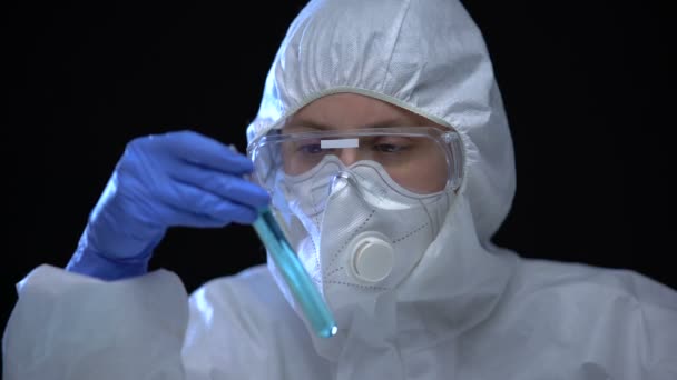 Giftige laboratoriummedewerker die blauwe vloeistof bestudeert in reageerbuis met schadelijk teken - Video