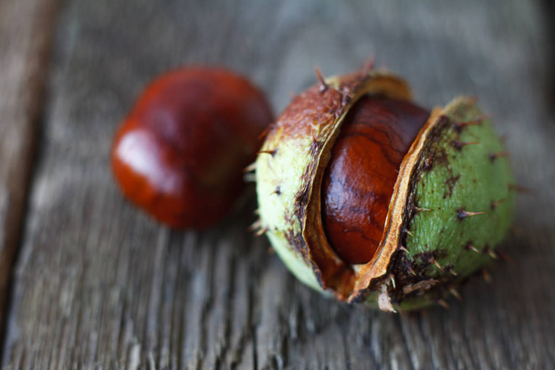 Extrémní uzavření několika zralých kaštanových ořechů na tmavém dřevěném stole, selektivní zaměření - Fotografie, Obrázek