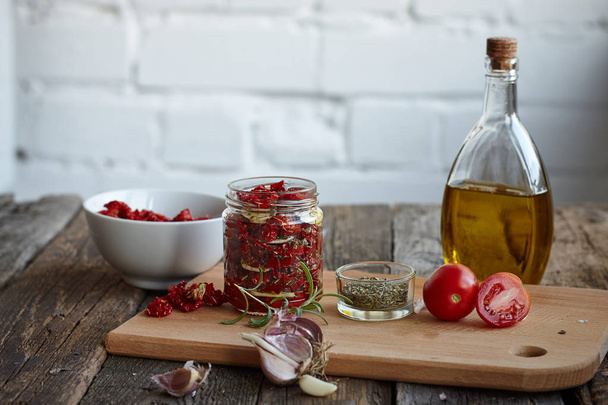 Sun-dried tomatoes with Provencal herbs, garlic and olive oil on a rustic wooden surface, selective focus - Zdjęcie, obraz