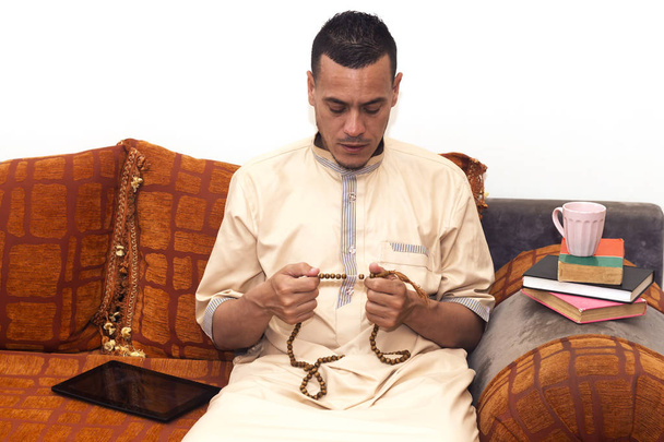 イスラム教徒の男性は、タスビでカウントし、コーヒーを飲んで、本を読んで追跡するためにミスバハを使用しています  - 写真・画像