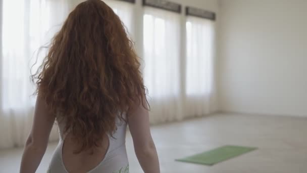 Close-up van jonge vrouw betreed lichte yoga studio met grote ramen in slow motion. - Video