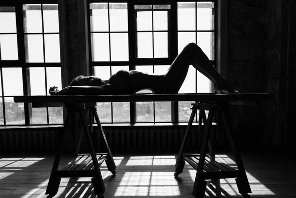 Black and white portrait of sexy beautiful young lady over light window background - Valokuva, kuva