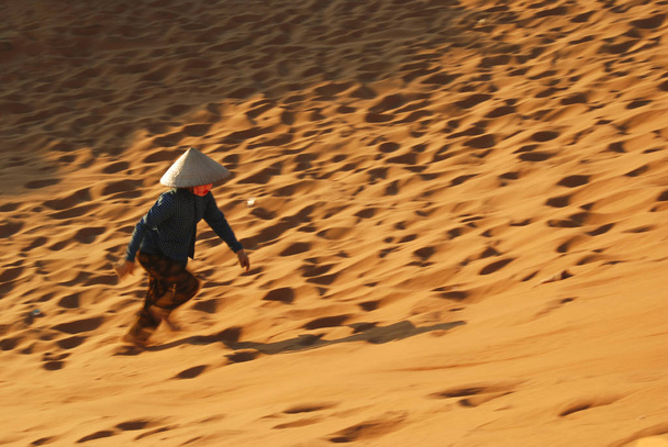 A Vietnamese woman running in sand of Red Sand Dunes of Mui Ne, Vietnam  - Photo, Image