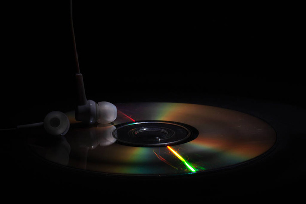CD компакт-диск и белые наушники на темном фоне. Концепция: слушать музыку
 - Фото, изображение