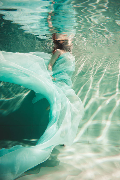 young woman swimming alone with fashion fabric underwater incognito - Foto, immagini