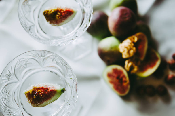 beautiful crystal champagne glasses with figs and nuts on table - Фото, зображення