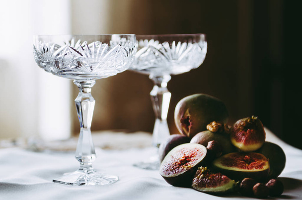 bellissimi bicchieri di champagne di cristallo con fichi e noci sul tavolo
 - Foto, immagini