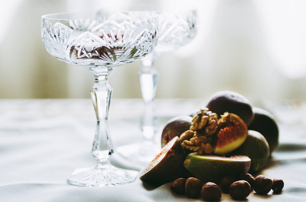 beautiful crystal champagne glasses with figs and nuts on table - Foto, afbeelding
