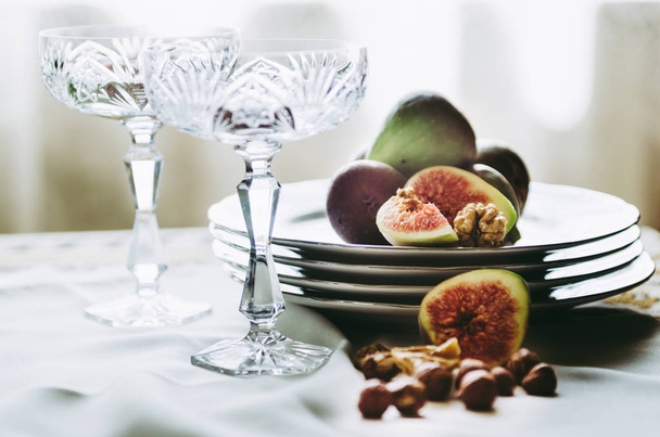 mooie kristallen Champagne glazen met vijgen en noten op tafel - Foto, afbeelding