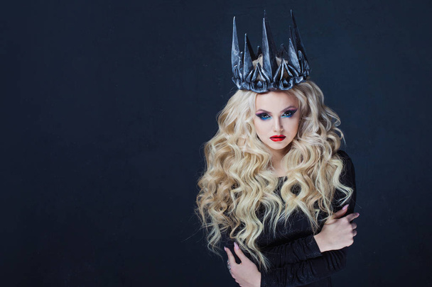 Portrait of a Gothic Queen. Beautiful young blonde woman in metal crown and black cloak. - Fotoğraf, Görsel
