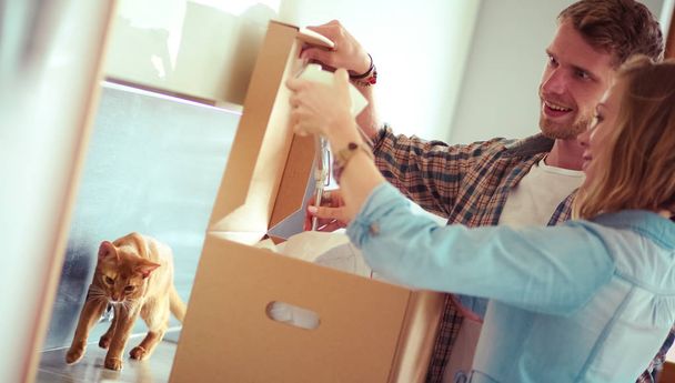Young couple carrying big cardboard box at new home.Moving house. Young couple - Photo, image