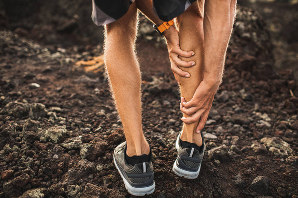 Mannelijke runner Holding geblesseerd kalf spier en lijden met pijn. - Foto, afbeelding