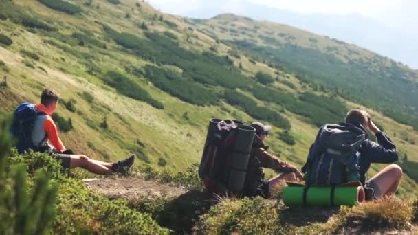 Trzy turyści siedzący na górskim wzgórzu w lecie. - Materiał filmowy, wideo