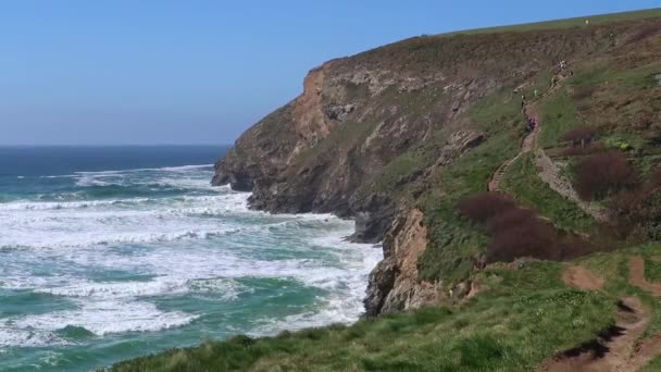 Langzame beweging van wandelaars op het South West Coast Path bij Mawgan Porth, North Cornwall, Engeland - Video