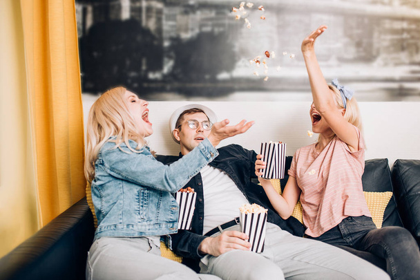 Cheerful group of friends eating popcorn at home - Valokuva, kuva