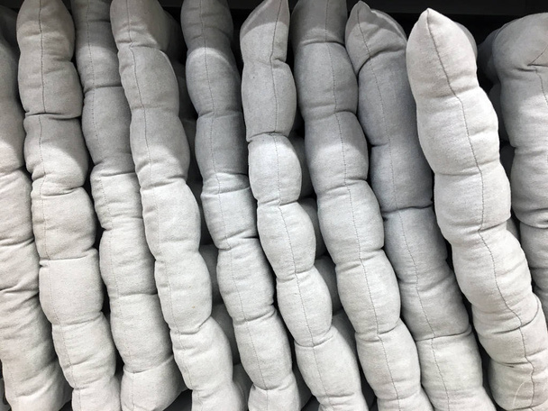 Pillow Seats on a shelf in a store. Soft gray seat cushions. Decorative Chair Cushion Sofa Soft Seat Comfortable. Thin pillows in a row - Photo, Image