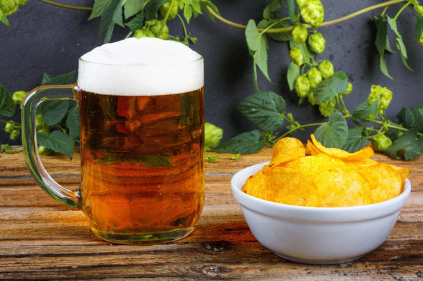 Стеклянная кружка холодного свежего золотого пива с крекерами и чипсами на w
 - Фото, изображение