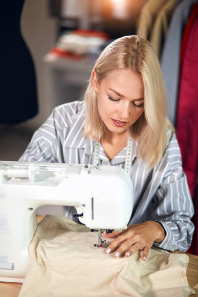Young dressmaker sews clothes on sewing machine. small business - Фото, зображення