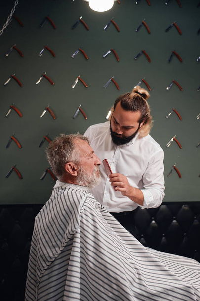 bearded barber brushing old mans hair - Zdjęcie, obraz