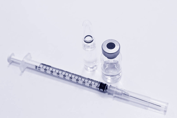 Frasco para injetáveis e ampola de medicamentos ou vacinas e seringa de plástico de 1 ml com agulha isolada no fundo branco, tom azul
 - Foto, Imagem