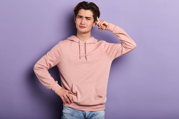 Closeup portrait, of young puzzled man in stylish pink hoodie scratching head - Fotó, kép