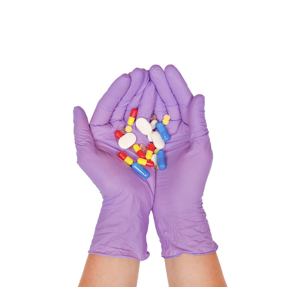 Handflächen in lila Latex-Handschuhen halten eine Handvoll Pillen - Foto, Bild
