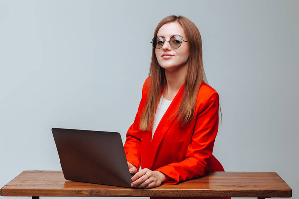Chica en una chaqueta roja y gafas con un ordenador portátil
 - Foto, imagen